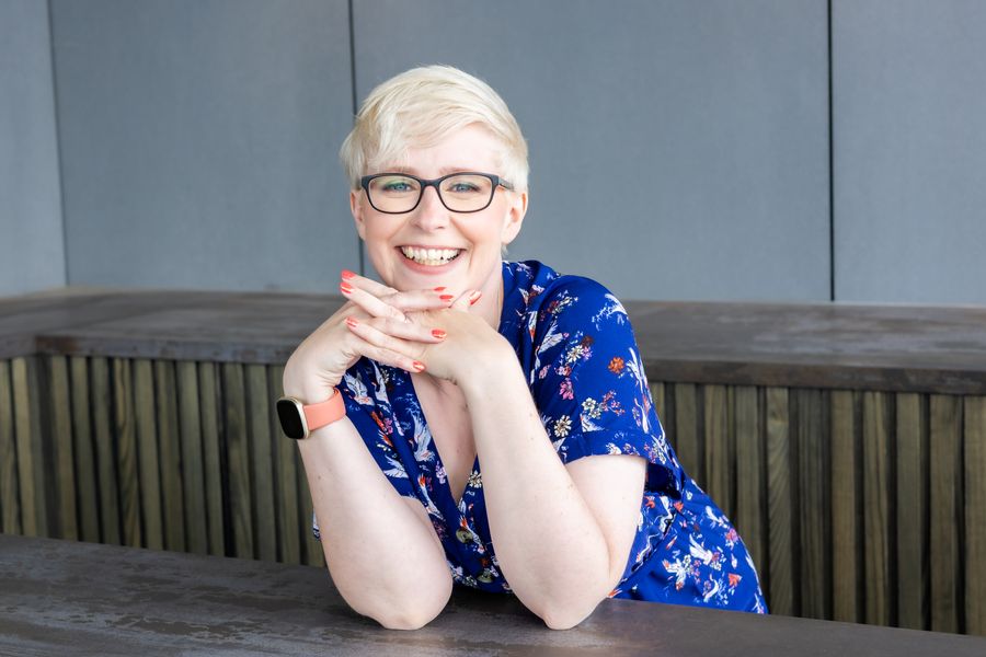 Jenny Lucas in a blue patterned dress, chin on her hands, smiling
